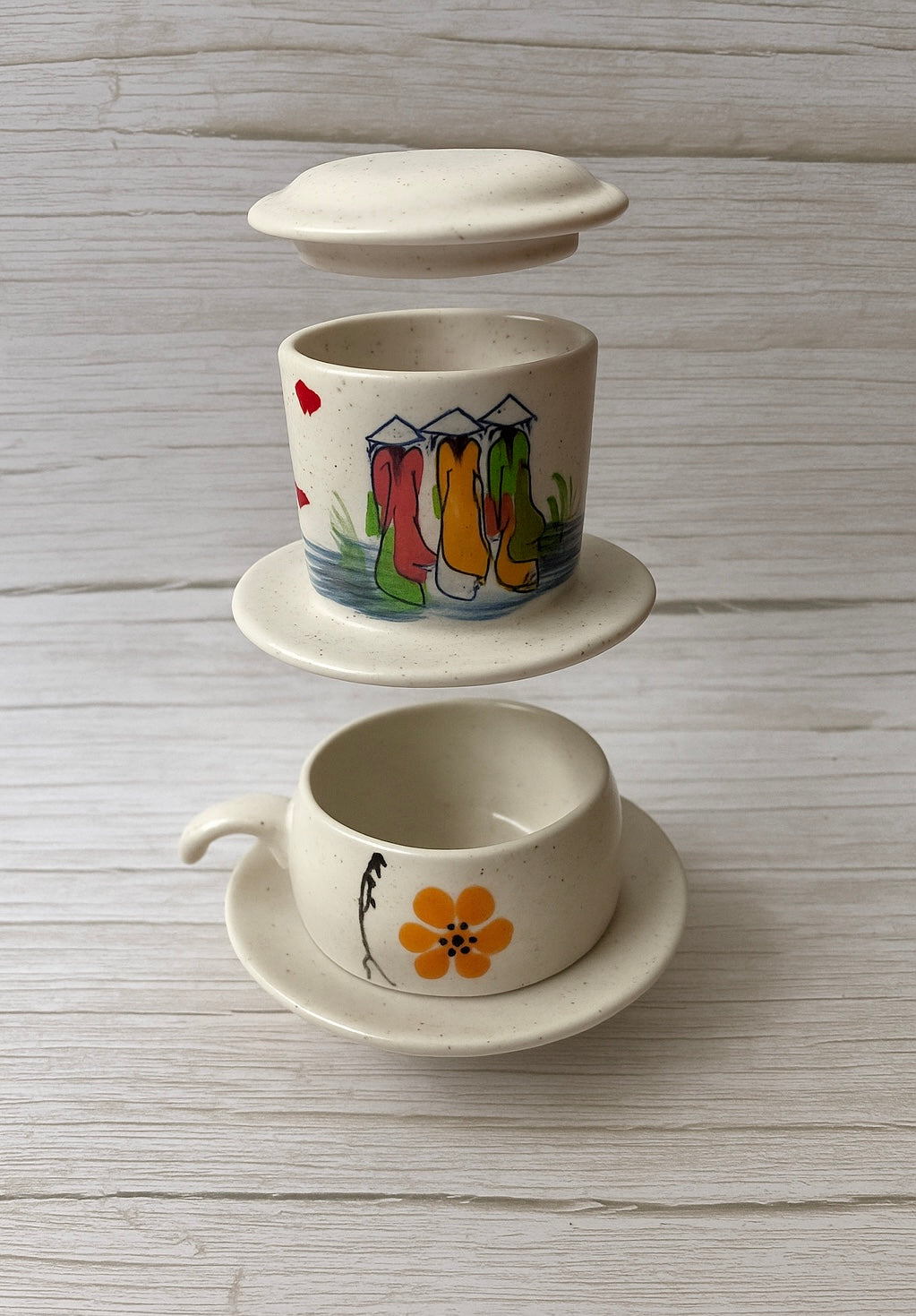 Weißer Phin- Kaffeefilter und passende Tasse aus Keramik mit einem Gemälde vietnamesischer Frauen in Ao dai